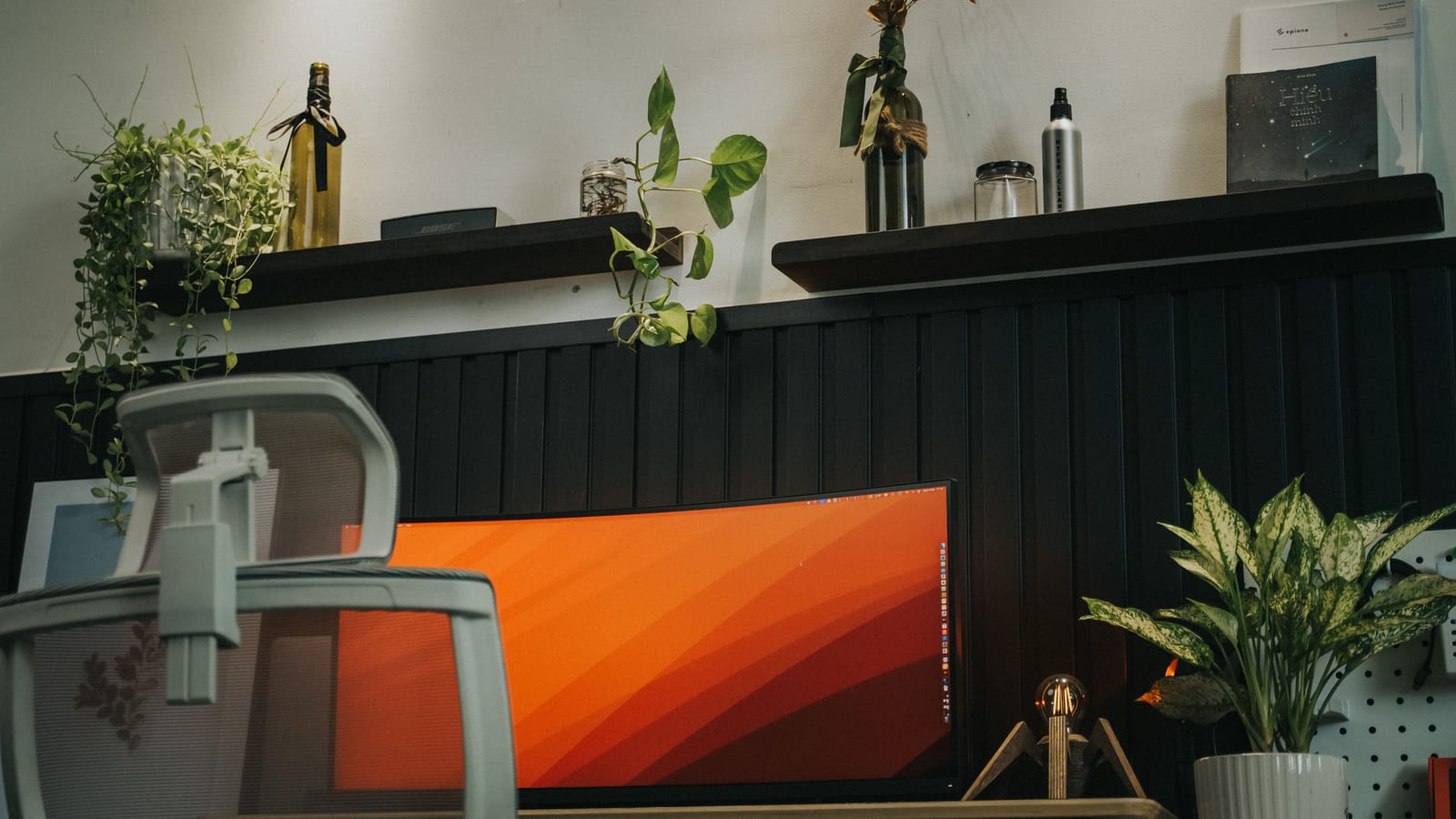 Stylish home office setup featuring a curved monitor, ergonomic chair, and indoor plants for a modern workspace vibe.
