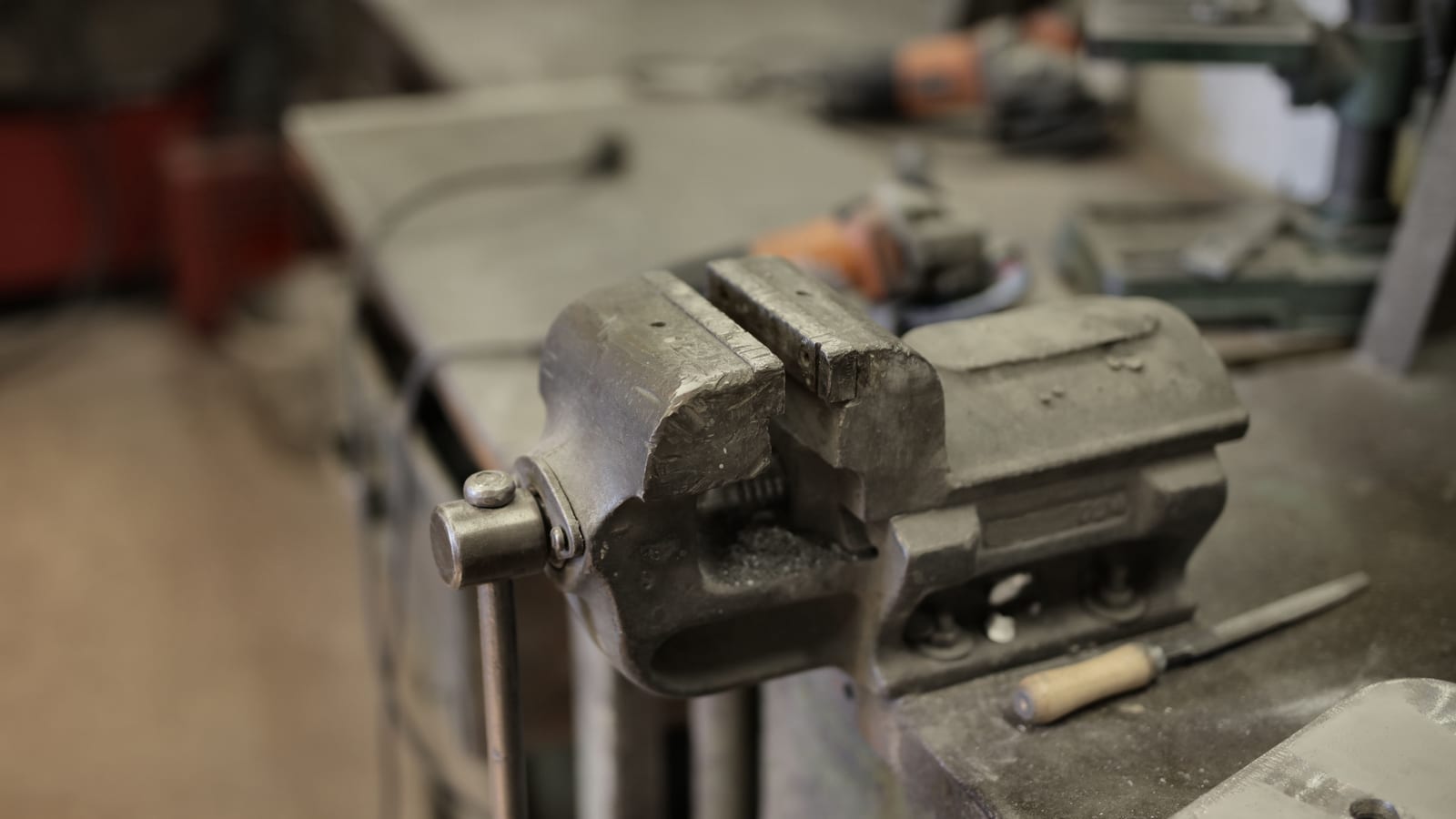 From above of vise fixing at workbench among different tools in workshop